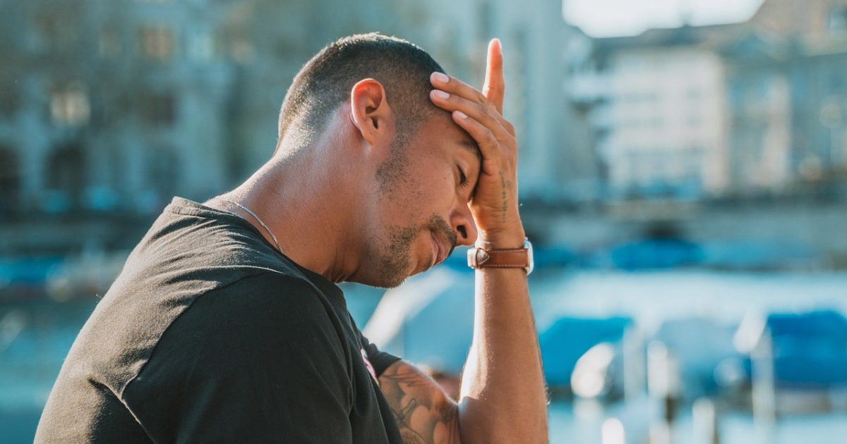 Man looking tired holding his face in his hand